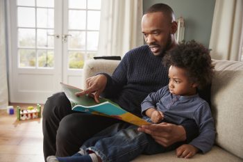 Father And Young Son Reading Book Together